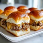 Close-up of several Cheesy Ground Beef Sliders with melted cheddar cheese and caramelized onions on soft buns.