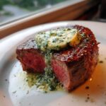 Close-up of a medium-rare Filet Mignon with Garlic Herb Butter melting on top.