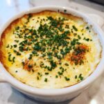Close-up of baked Garlic Herb Beer Cheese Fondue, bubbling and topped with fresh chives.