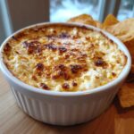 Close-up of baked Hot Mexican Street Corn Dip with a browned, cheesy top, served with tortilla chips.