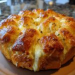 Close-up of baked Pull-Apart Ham and Cheese Sliders with melted, gooey cheese oozing out.