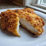 Close-up of perfectly cooked air fryer fried chicken, cut open to show juicy white meat inside crispy golden breading.