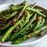 Close-up of perfectly roasted green beans seasoned with crispy, browned breadcrumbs.