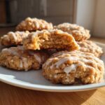 A stack of crumbly coffee cake cookies drizzled with white glaze, one cookie is broken open.