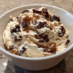 Close-up of creamy onion dip topped with dark, caramelized onions served in a small white bowl.