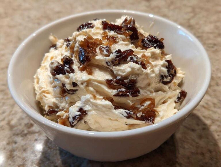 Close-up of creamy onion dip topped with dark, caramelized onions served in a small white bowl.