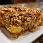 Close-up of a moist slice of apple crisp recipe showing tender apples and a thick, crunchy oat topping.