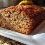 Close-up of a slice of the best banana bread showing its moist, golden-brown crumb and caramelized top.