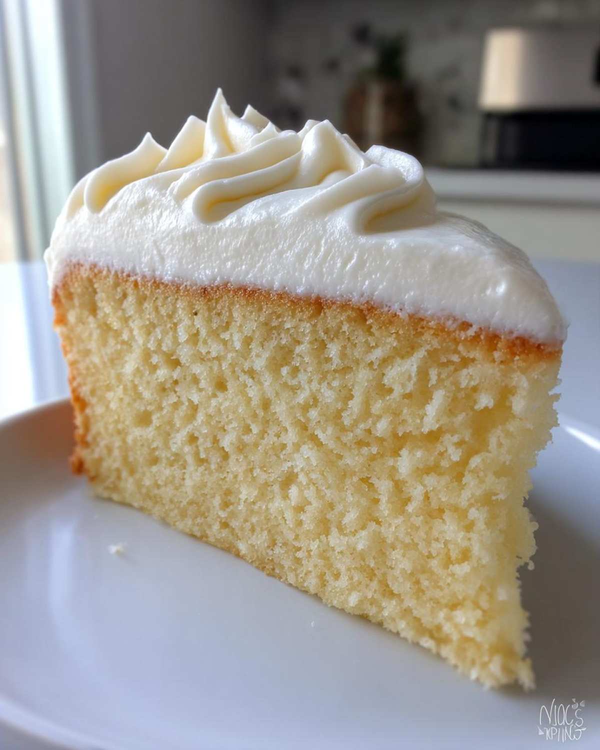 Close-up of a moist cake slice topped with perfectly piped vanilla buttercream frosting.