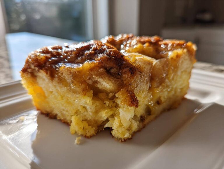 Close-up of a moist slice of caramel apple dump cake with a gooey, caramelized topping.