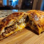 Close-up of delicious garbage bread cut in half showing melted cheese and savory ground meat filling.