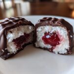 Close-up of chocolate covered cherries cut in half, showing the white filling and cherry center.