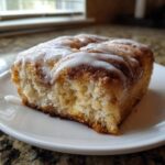 Close-up of a square slice of cinnamon roll french toast topped with thick white icing.