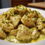 Close-up of tender chicken pieces coated in a creamy, bright sauce, garnished with lime zest and herbs for coconut lime chicken.
