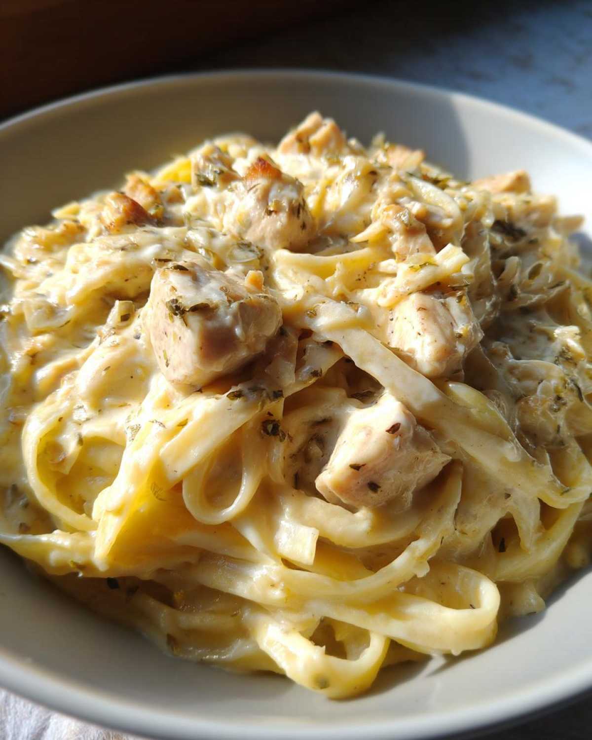 Close-up of creamy fettuccine pasta topped with chunks of seasoned chicken in a rich sauce, showcasing the chicken alfredo.