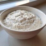 Close-up of creamy coconut chia pudding with visible black chia seeds in a white bowl.