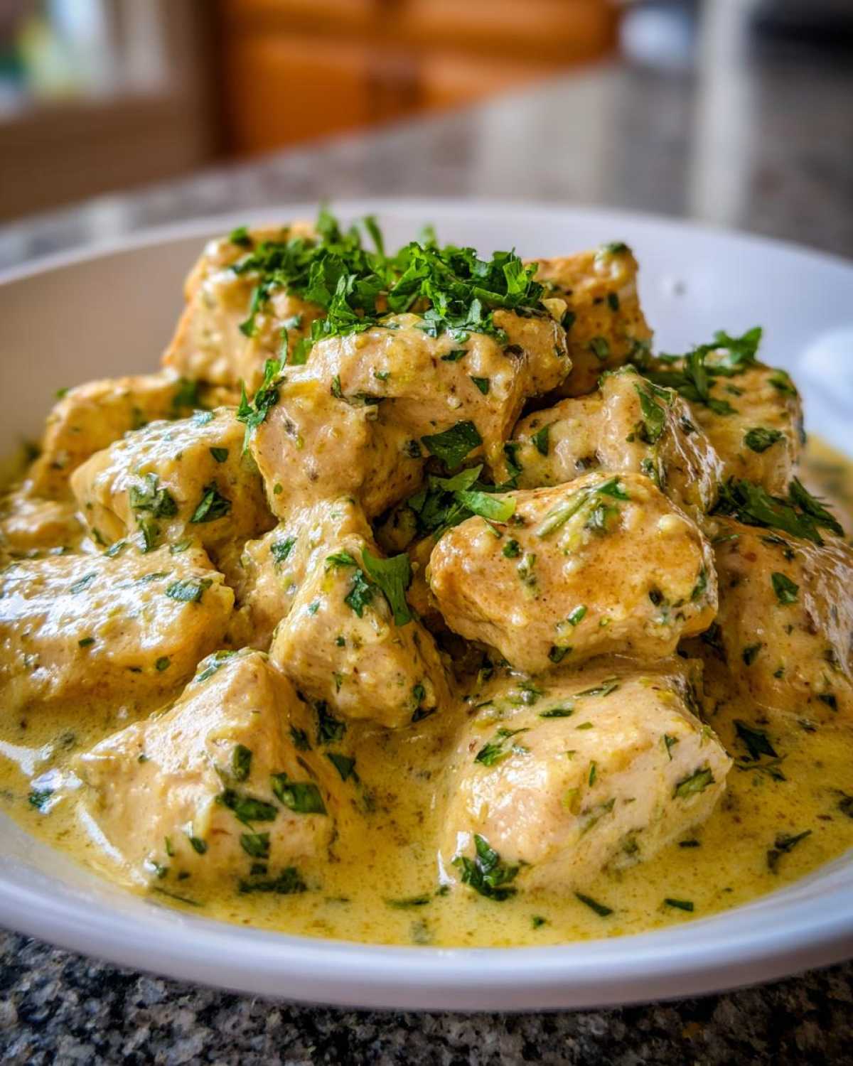 Close-up of tender chicken pieces coated in a rich, creamy coconut lime chicken sauce and topped with fresh parsley.