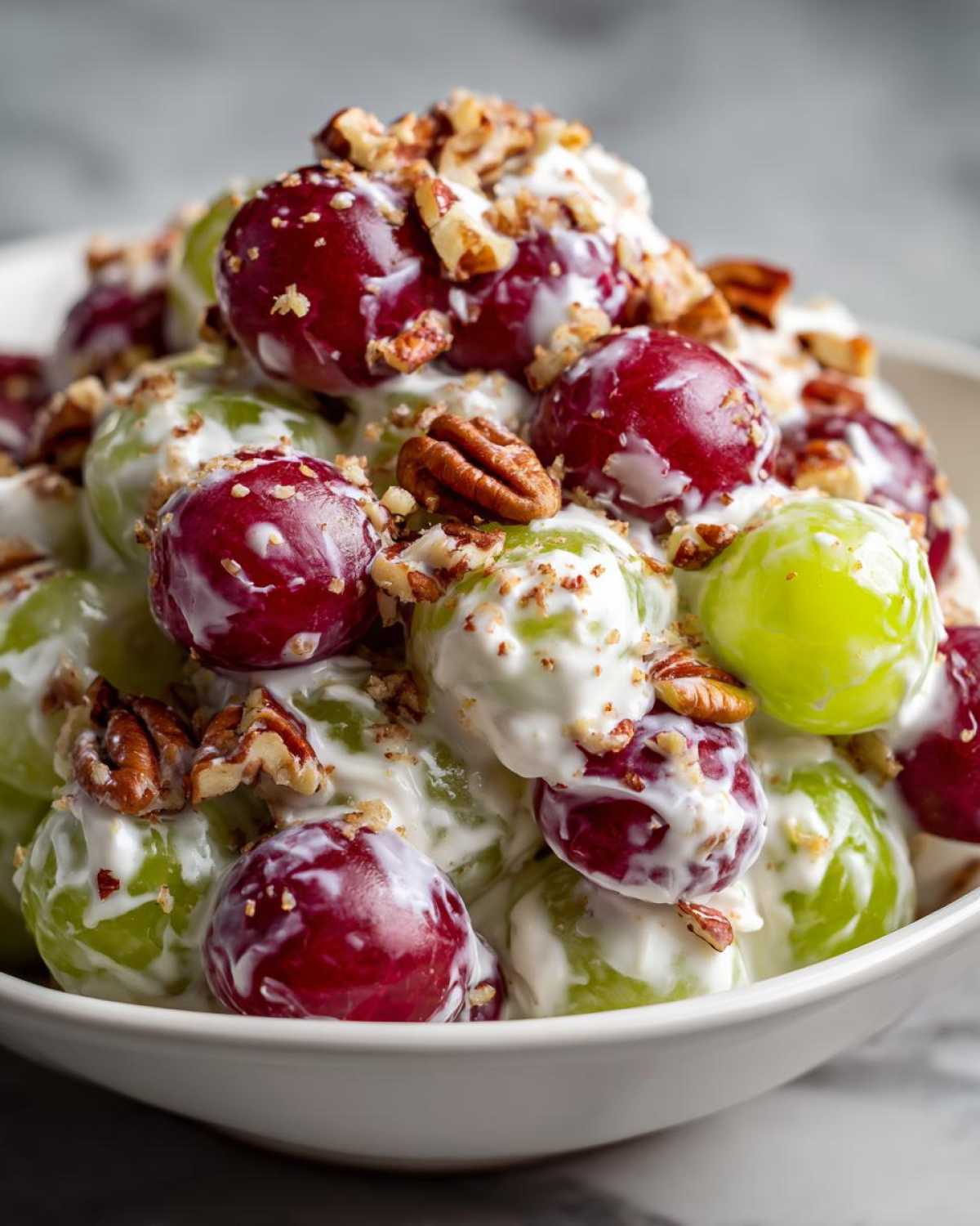 Close-up of creamy chicken salad chick grape salad mixed with red and green grapes and topped with chopped pecans.