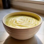 A close-up of a bowl filled with creamy leek soup, garnished with pepper.