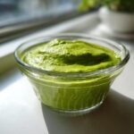 Close-up of creamy, bright green matcha chia pudding served in a small clear glass bowl.