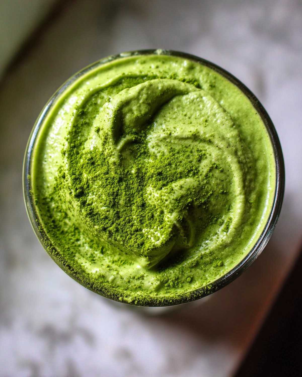 Overhead view of creamy matcha chia pudding topped generously with bright green matcha powder.