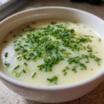 Close-up of a bowl of creamy potato leek soup topped generously with fresh, chopped green chives.