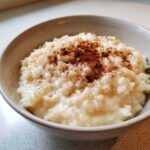 Close-up of a creamy bowl of homemade rice pudding topped generously with ground cinnamon.