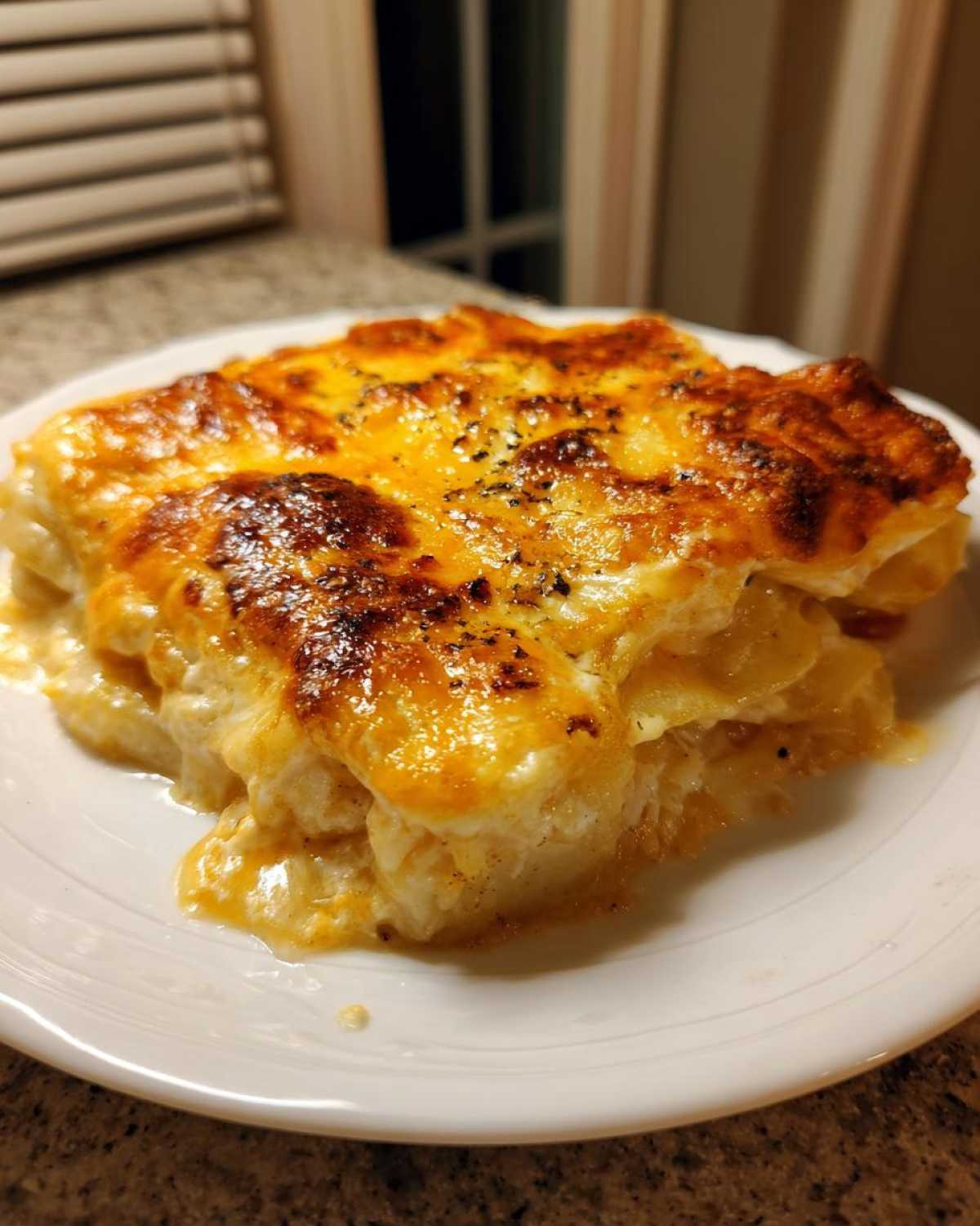 A close-up of a serving of creamy scalloped potatoes with a golden-brown, bubbly cheese topping.