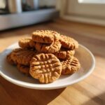A stack of freshly baked Easy Peanut Butter Cookies with classic fork cross-hatch marks on a white plate.