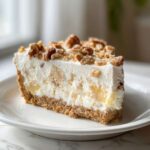A thick slice of creamy, no-bake Million Dollar Pie with a graham cracker crust, topped with pecans.