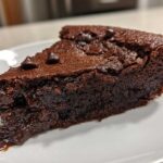A decadent slice of 350 calorie fudge pie with a molten chocolate center oozing onto a white plate.
