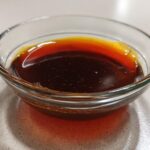 Close-up of rich, dark homemade teriyaki sauce in a clear glass dipping bowl.