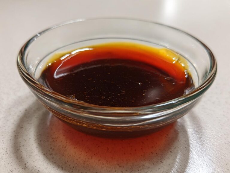 Close-up of rich, dark homemade teriyaki sauce in a clear glass dipping bowl.