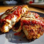 Close-up of a juicy chicken parmesan recipe cut in half, showing melted mozzarella cheese stretching from the crispy breaded chicken.