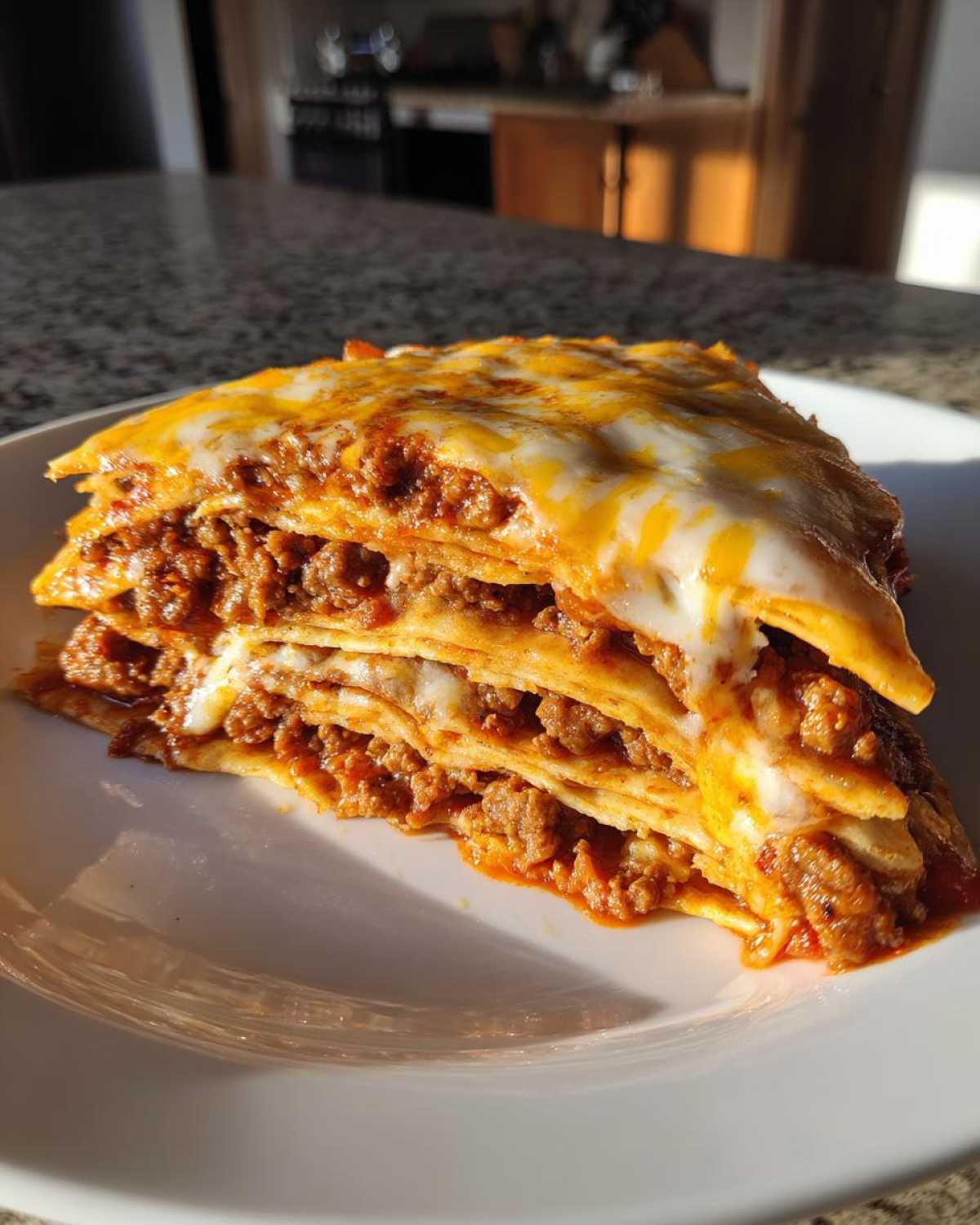 A thick, layered slice of Mexican pizza featuring seasoned ground meat and melted cheese on a white plate.
