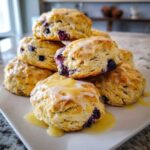 A tempting stack of fluffy lemon blueberry scones generously topped with a thick, dripping lemon glaze.