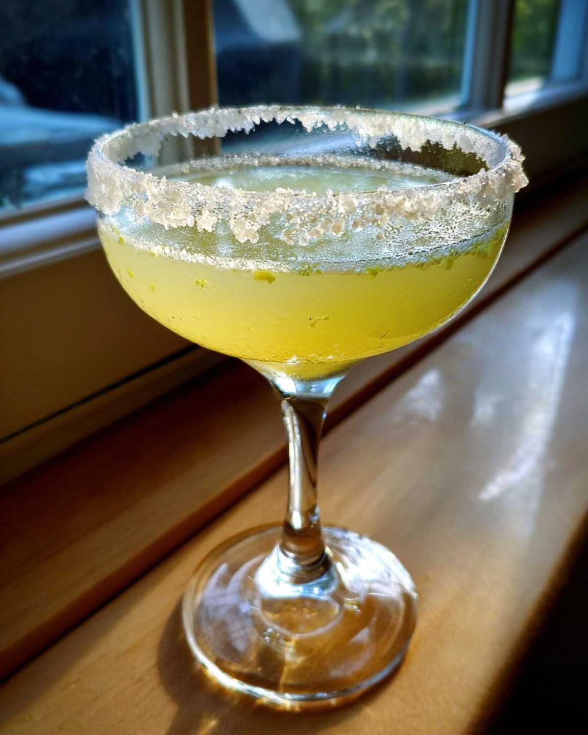 Close-up of a chilled lemon drop martini in a coupe glass with a heavily sugared rim.