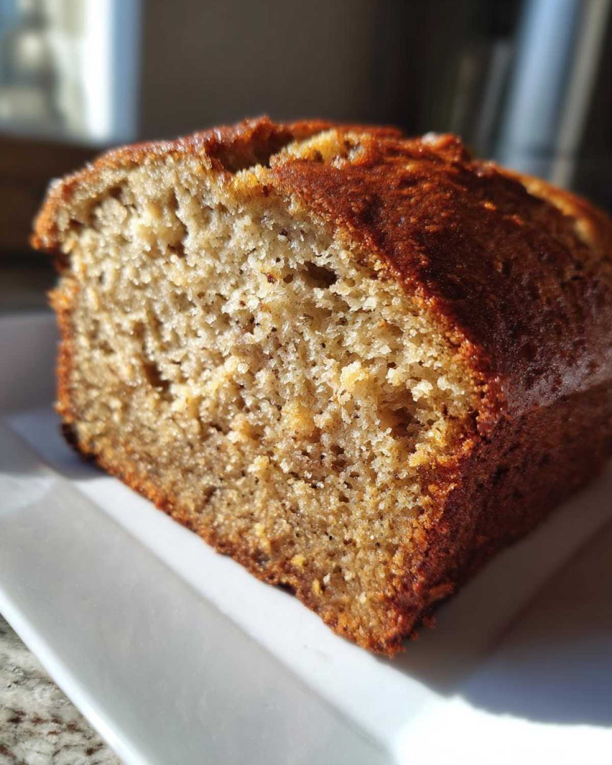 Close-up of a moist slice of the best banana bread showing its golden-brown crust and tender crumb.