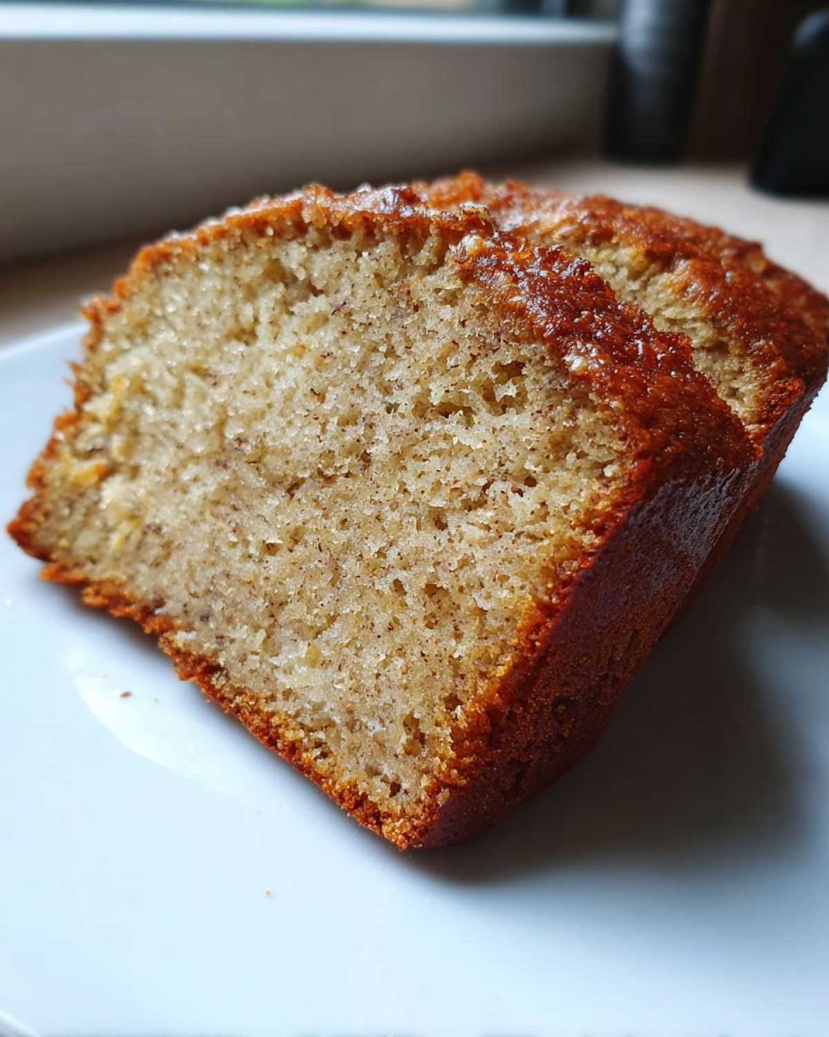 Close-up of a thick, moist slice of the best banana bread showing its tender crumb and golden-brown crust.