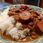 A close-up serving of flavorful beans and rice topped with sliced smoked sausage.