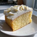 A close-up of a slice of yellow cake topped with perfectly piped vanilla buttercream frosting.