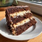 A decadent slice of german chocolate cake recipe showing dark chocolate layers and creamy coconut-pecan filling.