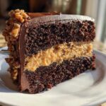 A decadent slice of german chocolate cake recipe showing dark chocolate layers and coconut-pecan filling.