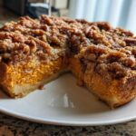 A slice cut from a round southern sweet potato casserole topped with a thick, crunchy brown sugar streusel topping.