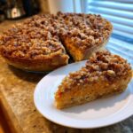 A slice of southern sweet potato casserole with a thick, crunchy pecan streusel topping served on a white plate.