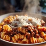 Close-up of a steaming bowl of crockpot lasagna soup featuring rotini pasta, rich meat sauce, and grated Parmesan cheese.