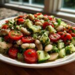 Close-up of a vibrant white bean salad featuring cannellini beans, halved cherry tomatoes, and diced cucumber.
