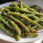 Close-up of crispy Air Fryer Garlic Parmesan Green Beans sprinkled with cheese, served in a white bowl.