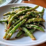 A close-up of crispy Air Fryer Garlic Parmesan Green Beans piled high on a white plate.