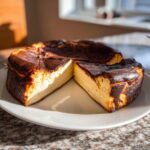 A whole basque cheesecake with two slices cut out, showing its creamy interior and dark, caramelized top.